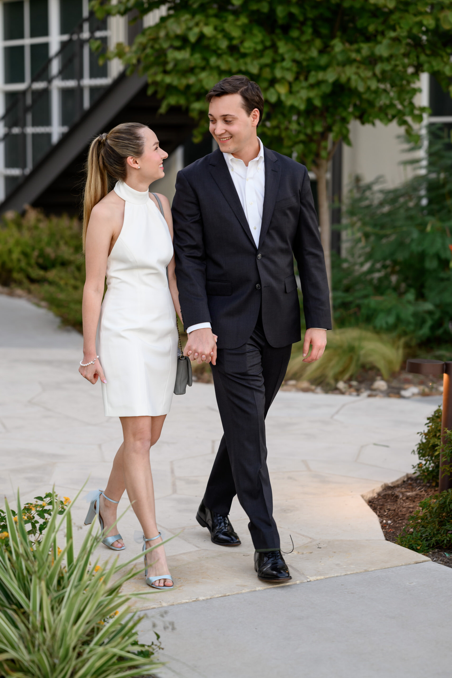 Couple walking hand in hand during a relaxed rehearsal dinner or wedding weekend celebration