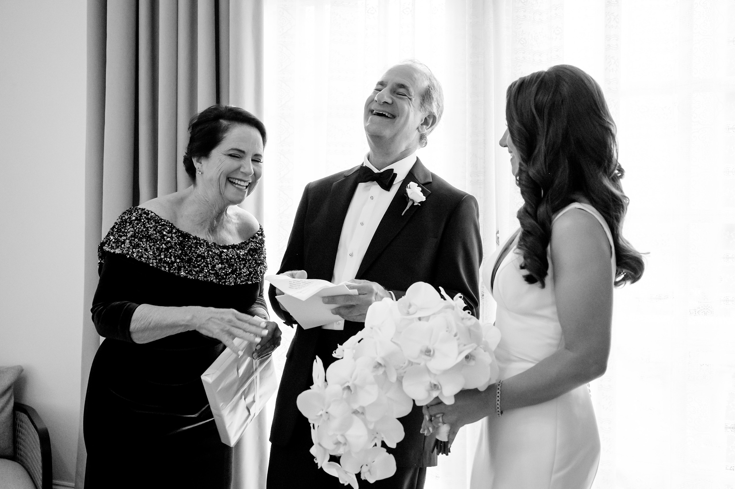 Black and white candid photo of a bride laughing with family before the ceremony