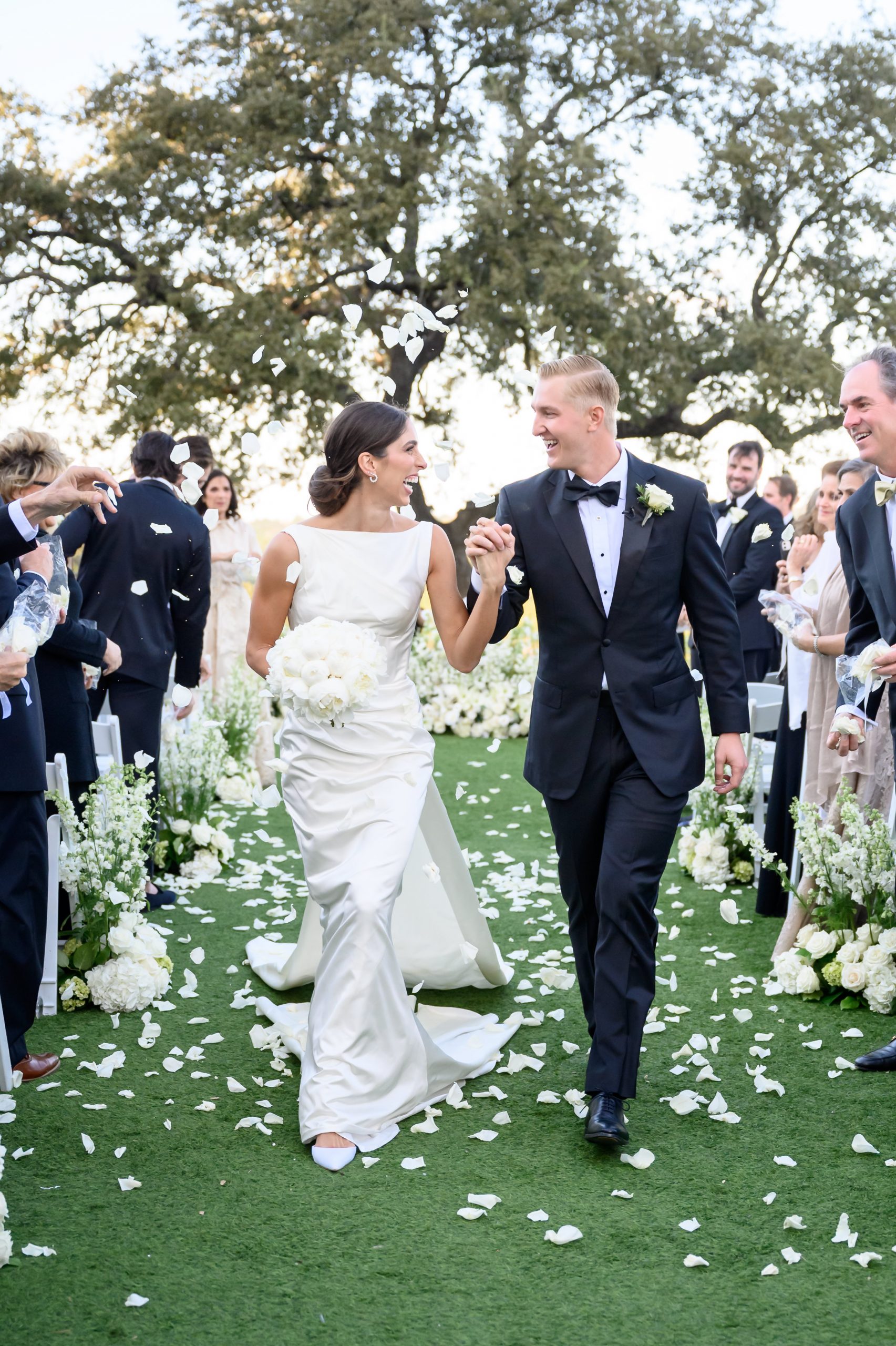 Bride and groom smiling as they walk back down the aisle after their outdoor wedding ceremony at Omni Barton Creek