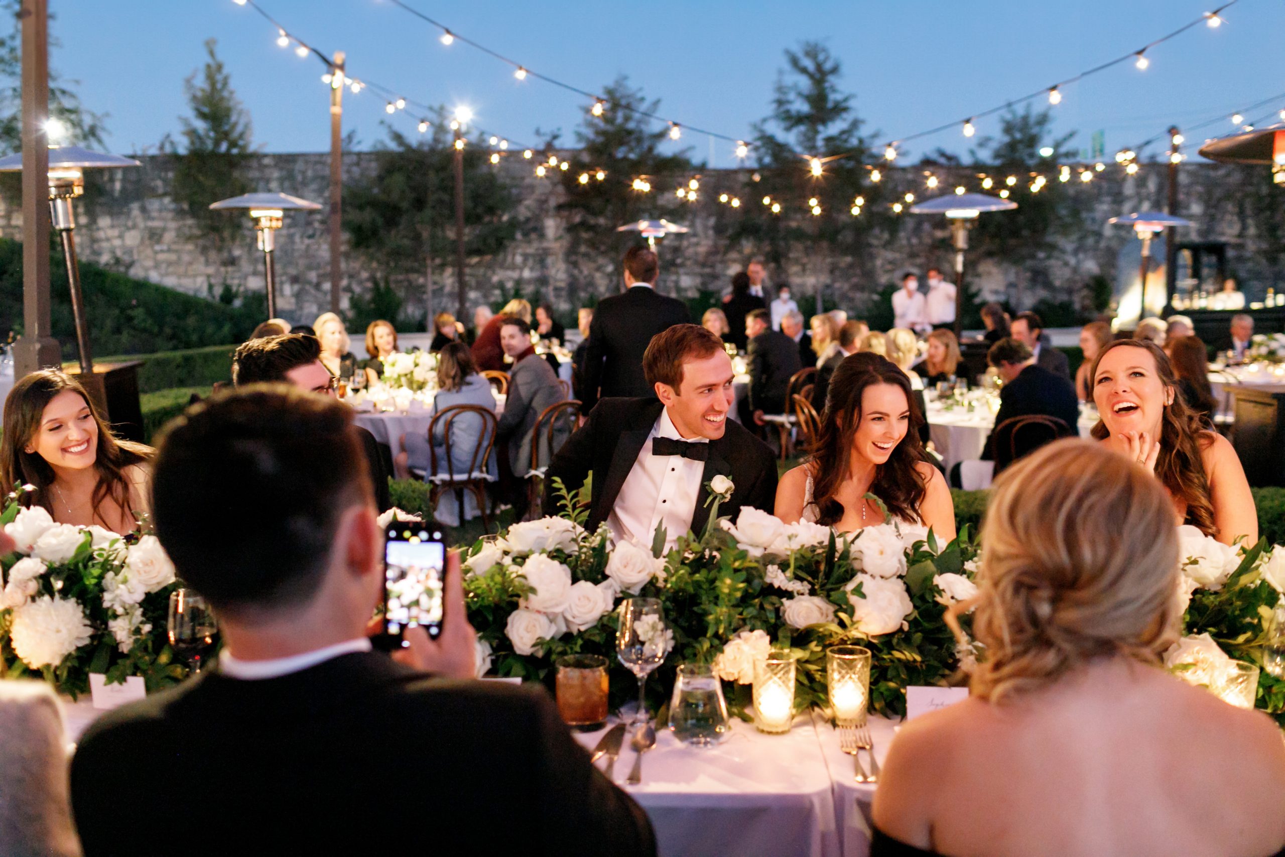 Bride and groom seated at an outdoor candlelit wedding reception at Commodore Perry Estate in Austin