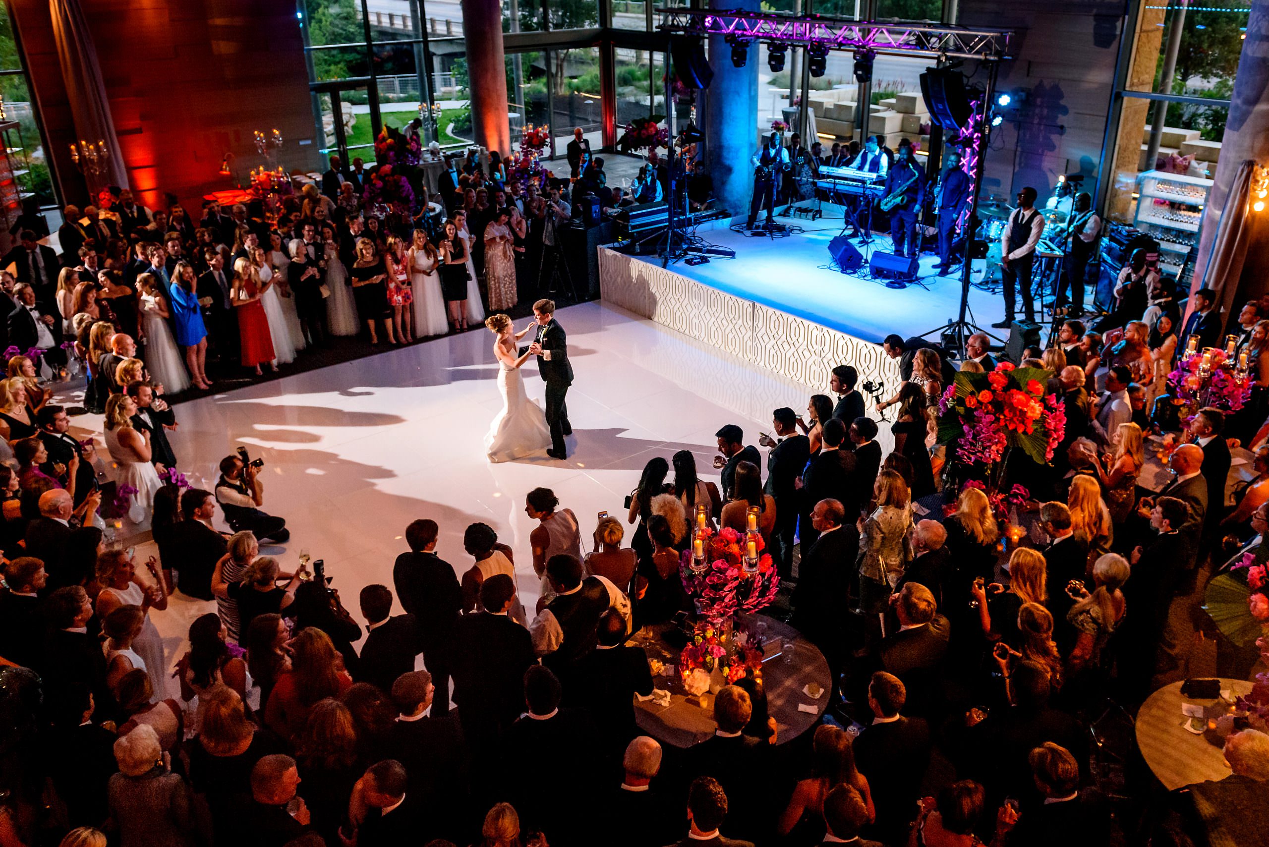 Wide view of a lively wedding reception with guests gathered around the dance floor