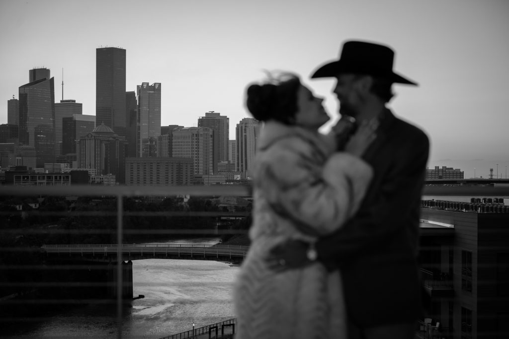 Bailey and Alton embracing on the terrace at Le Tesserae with the Houston skyline behind them.