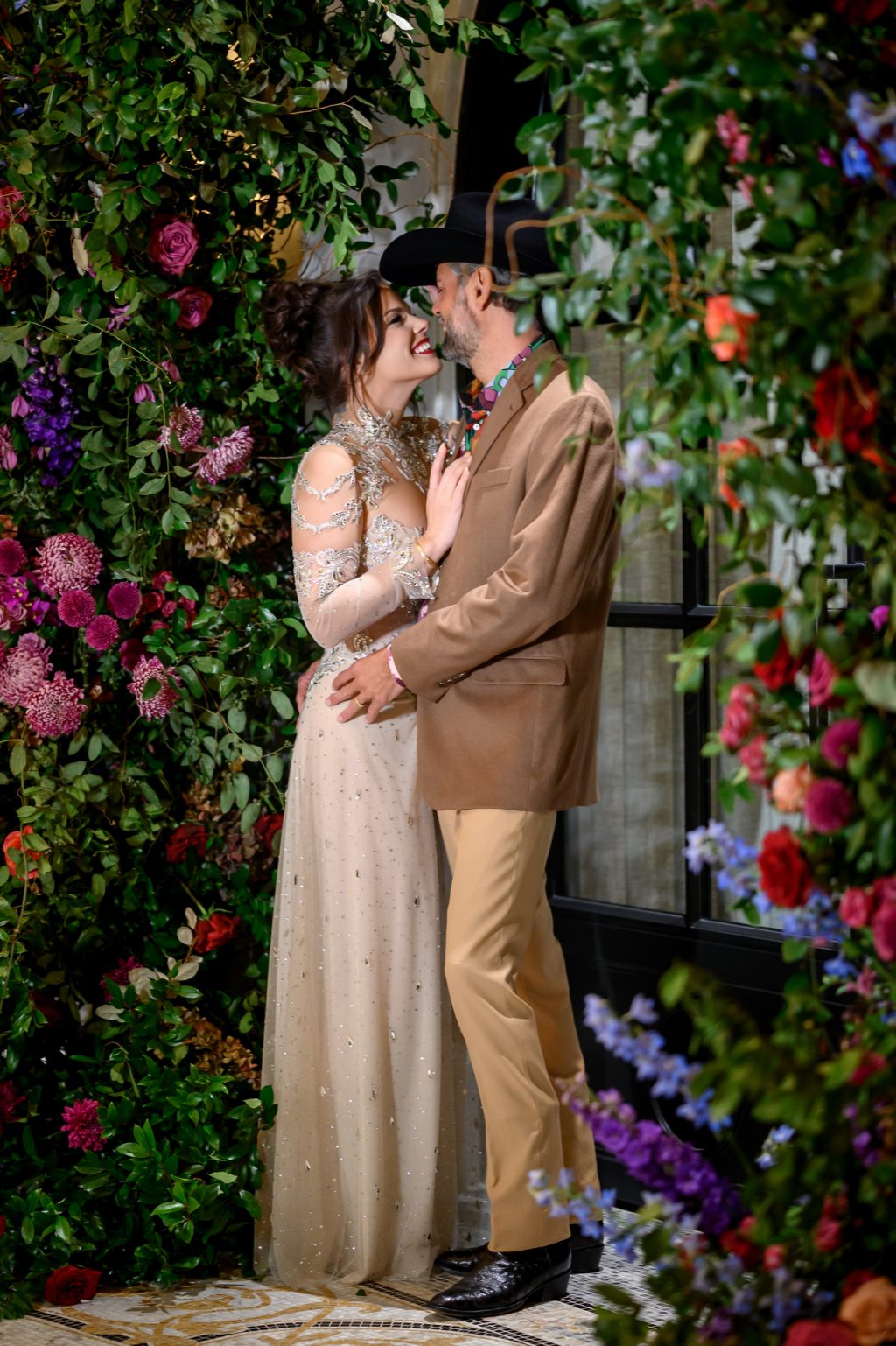 Bailey and Alton posing in front of a dramatic floral installation at Le Tesserae.
