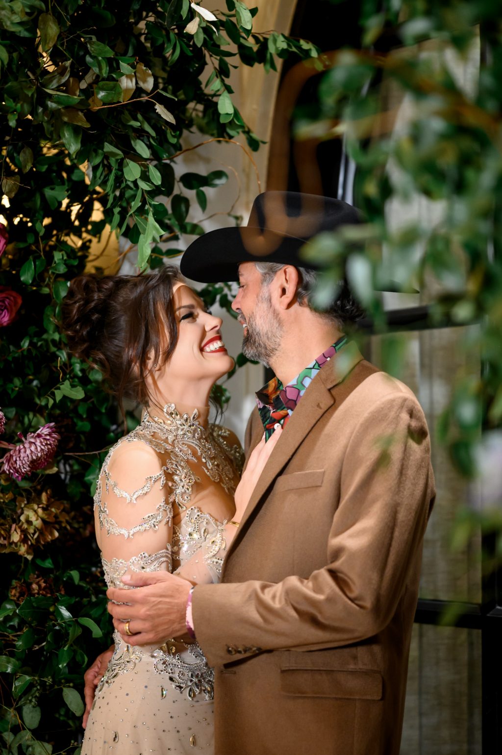 posing together in front of lush floral decor at Le Tesserae.