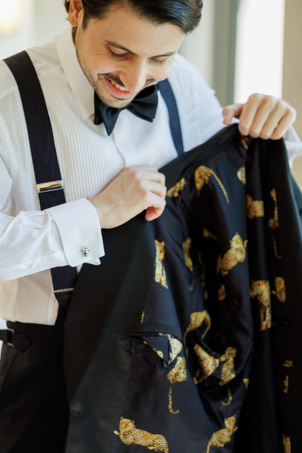 Groom getting ready in custom tuxedo with leopard print lining