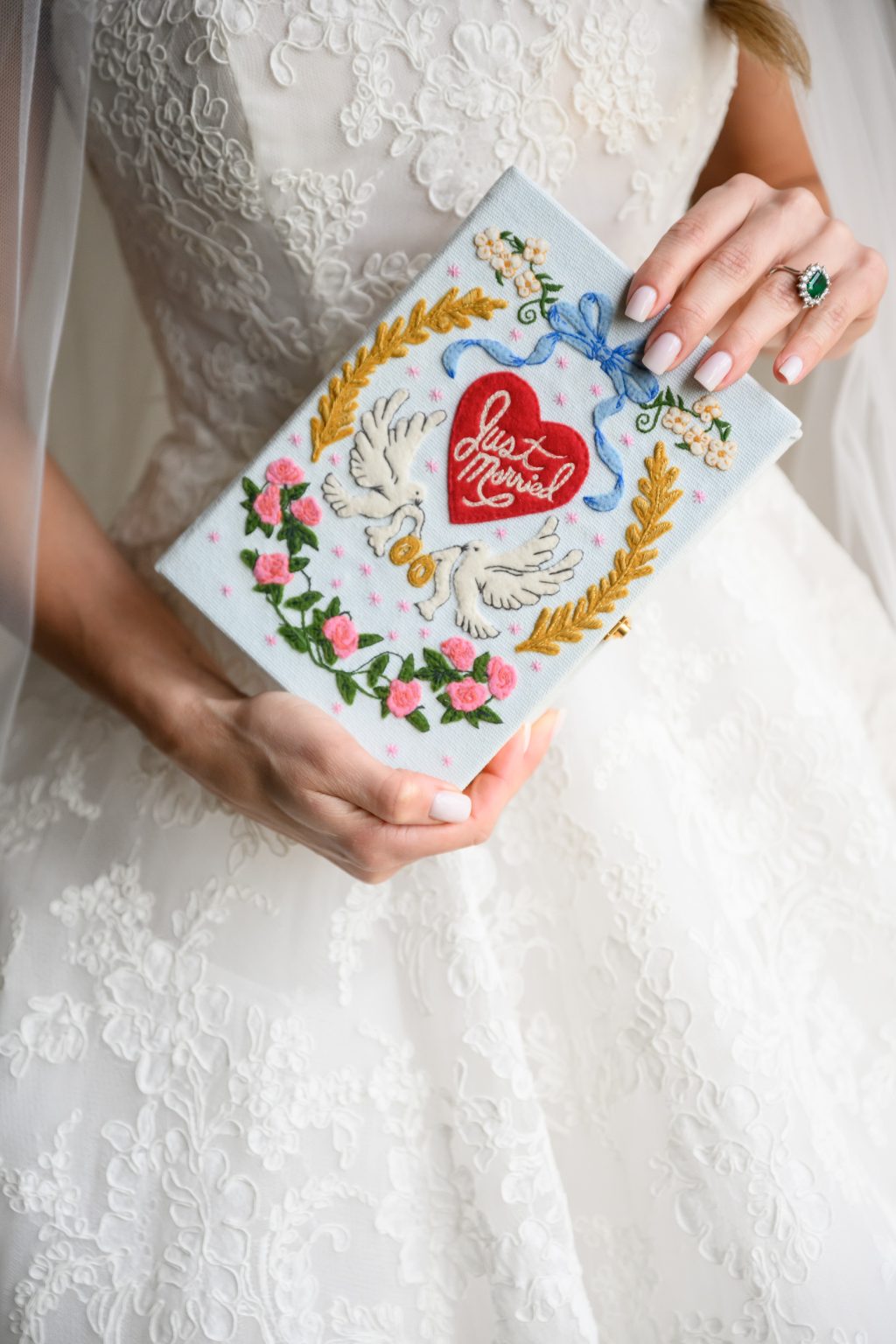 Bride holding Olympia Le Tan embroidered doves clutch with wedding dress