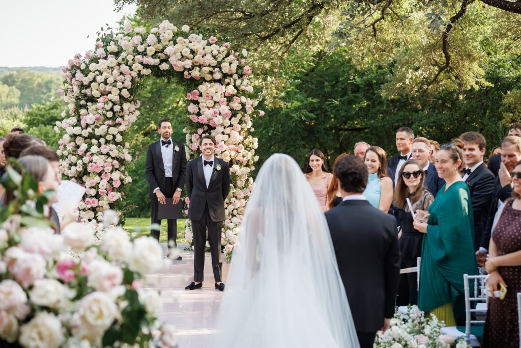 Outdoor wedding ceremony surrounded by pink florals and greenery at Four Seasons Austin