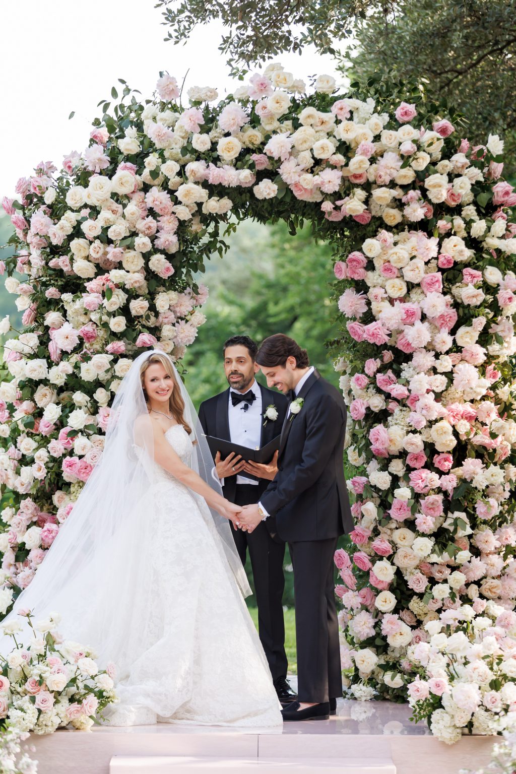 Bride and groom portrait beneath pink and white wedding flowers at Four Seasons Austin