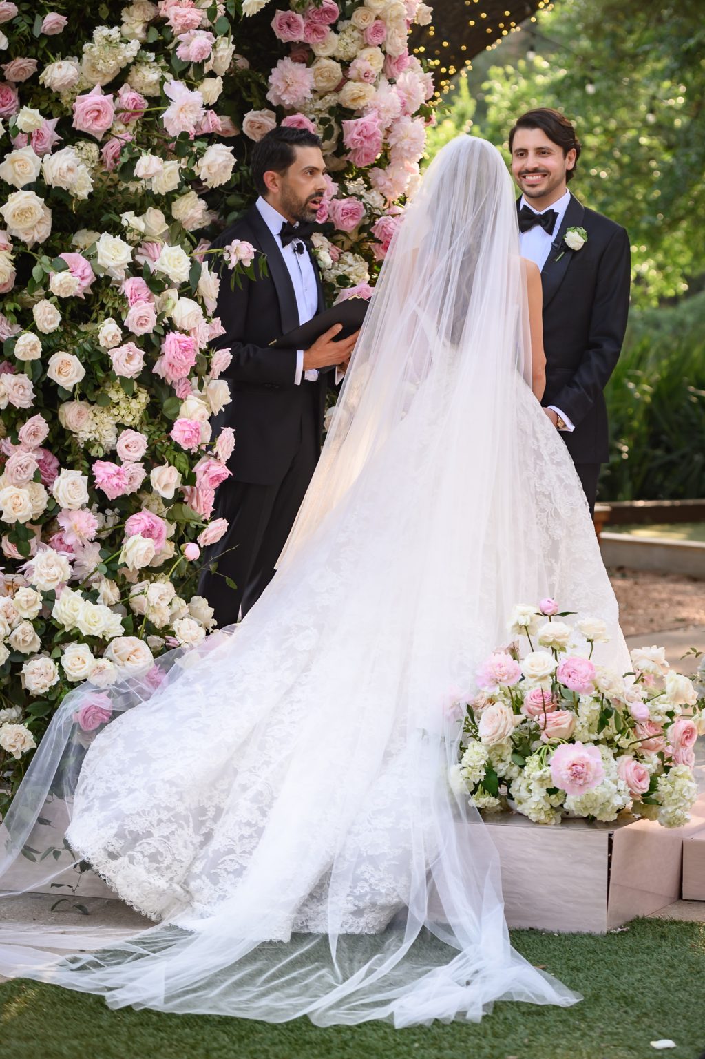 Bride walking beside lush pink and white floral ceremony installation at Four Seasons Austin
