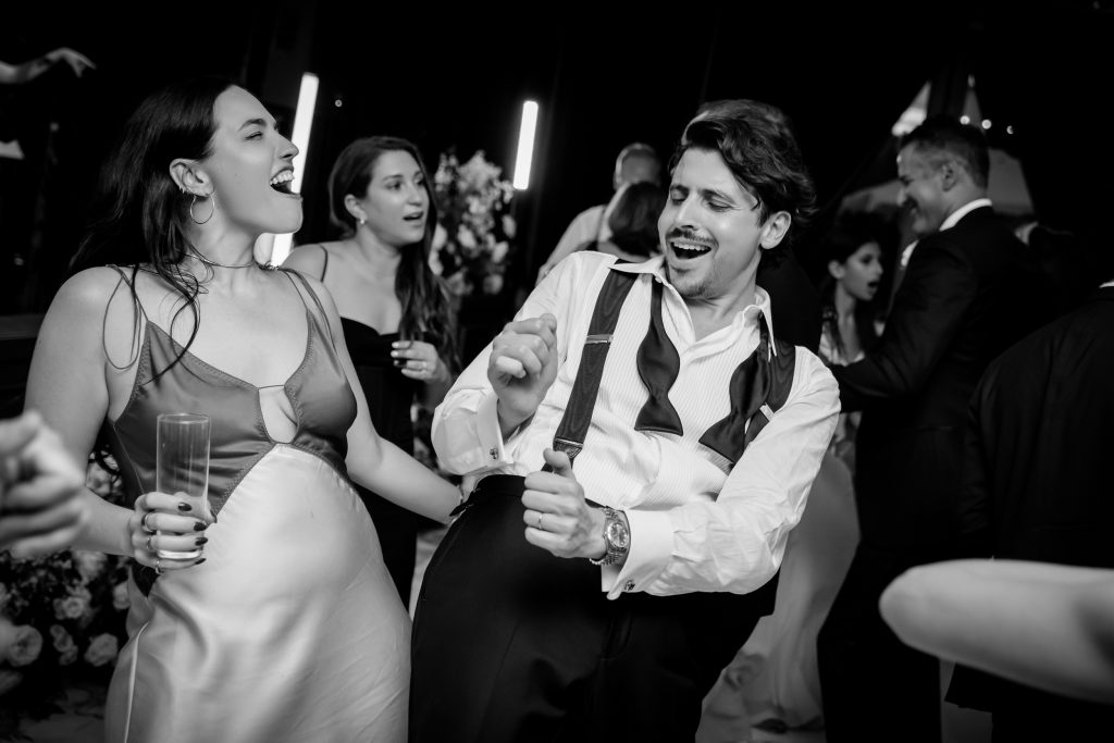 Black and white candid of groom laughing with friends during the reception