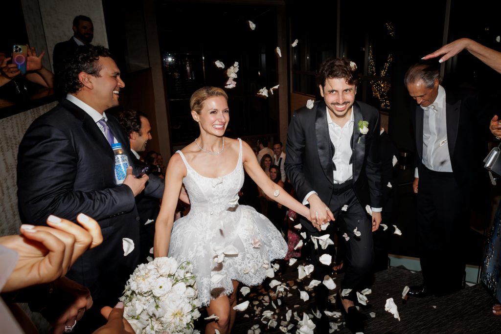 Bride and Groom exiting up the staircase with guests during a lively Four Seasons Austin wedding reception