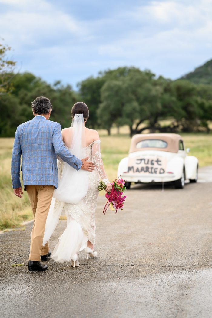 Couple walking back to their vintage vw bug car with the handmade "just married" sign on the back