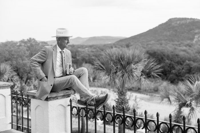 Candid black and white fine art of cowboy sitting on the railing in west texas