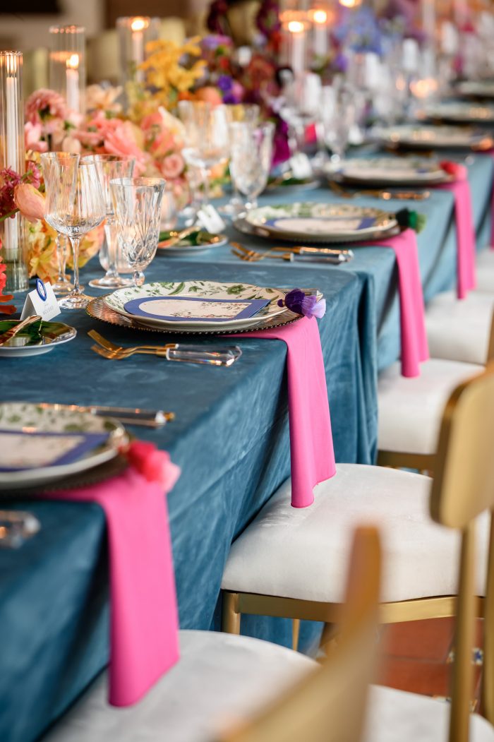 Reception table top with smoke velvet blue linen, bright fuschia napkins and green place settings including a green ginori butter plate