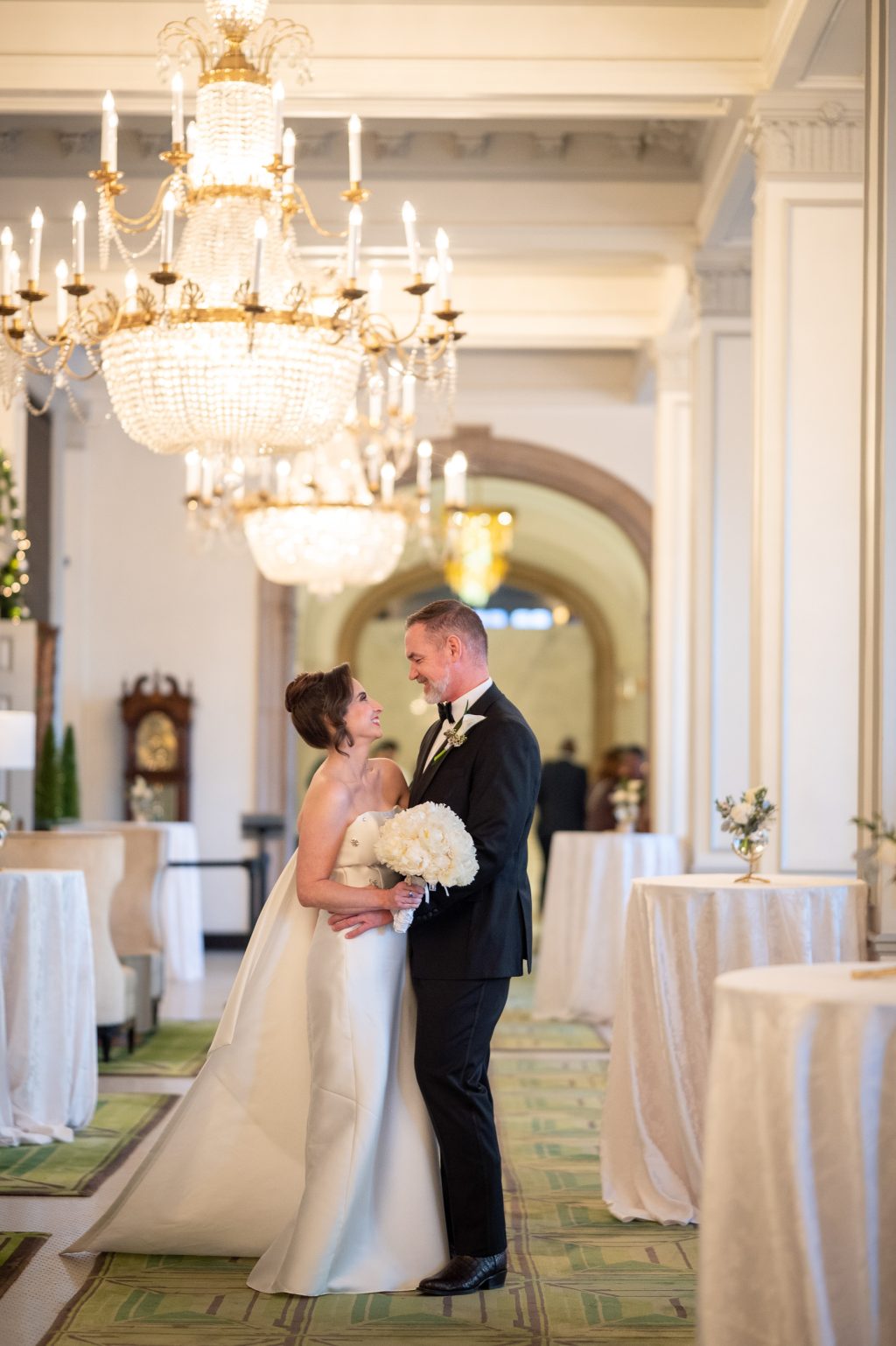 Bride and groom embracing beneath chandeliers inside The St. Anthony Hotel