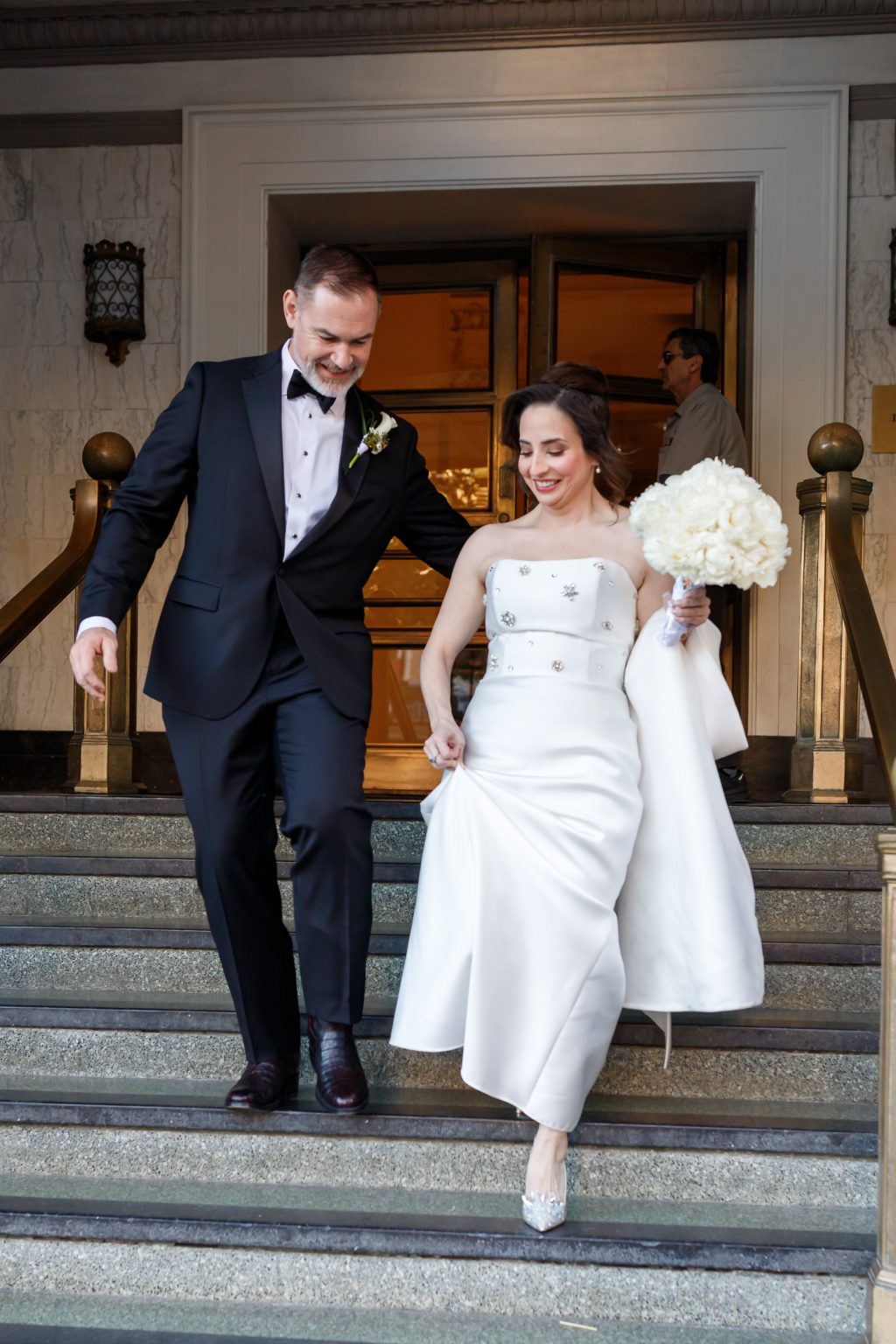 Bride and groom walking down the front steps of The St. Anthony Hotel in downtown San Antonio
