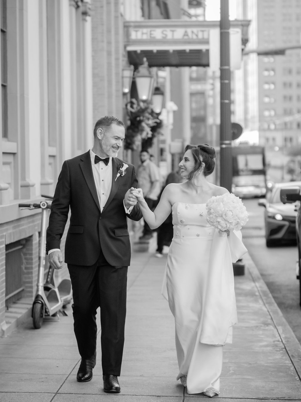 Black and white photograph of the bride and groom walking outside The St. Anthony Hotel