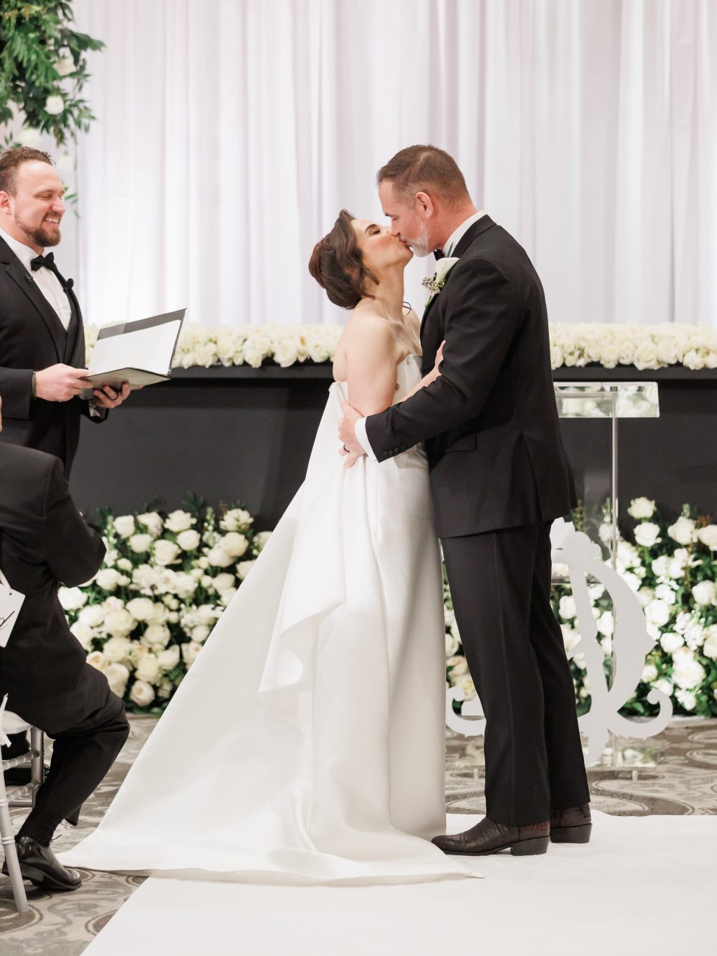 Bride and groom kissing during their wedding ceremony at The St. Anthony Hotel in the Peraux room.