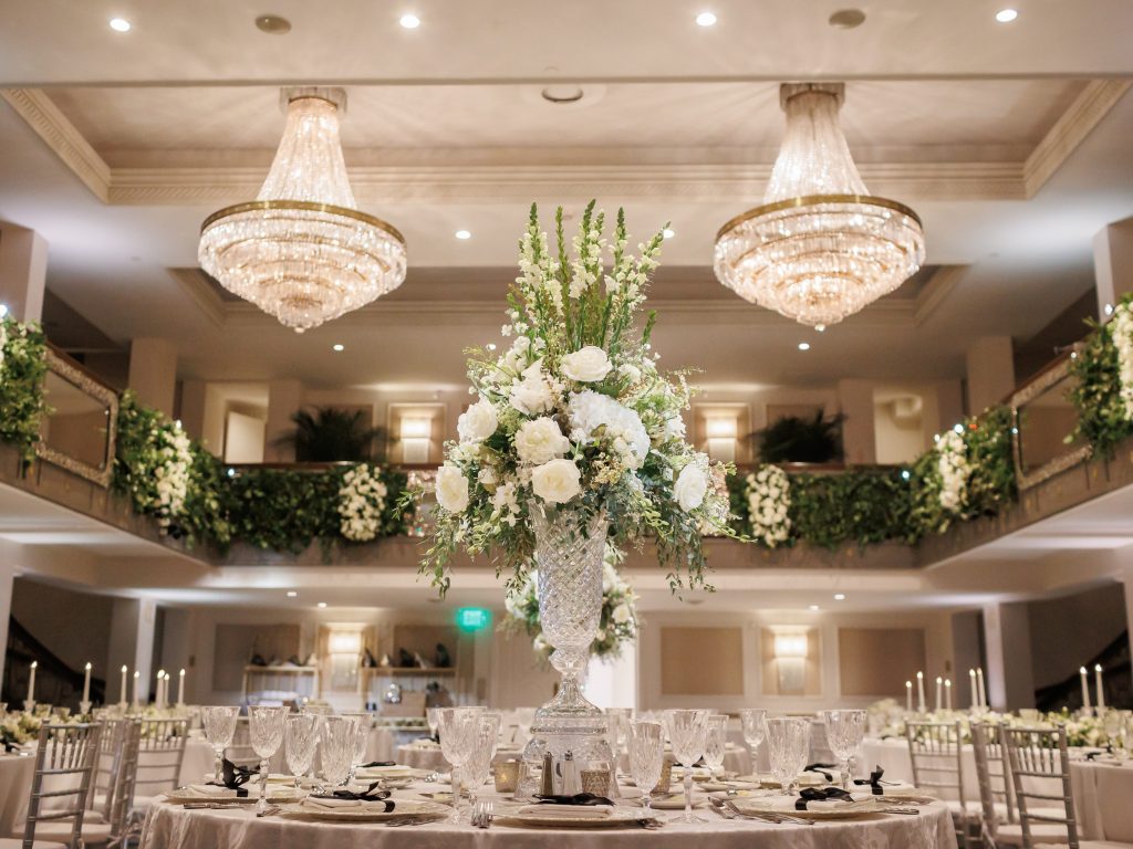 White floral reception design beneath chandeliers in Anacacho ballroom at The St. Anthony Hotel designed by Wilkinson Rhodes