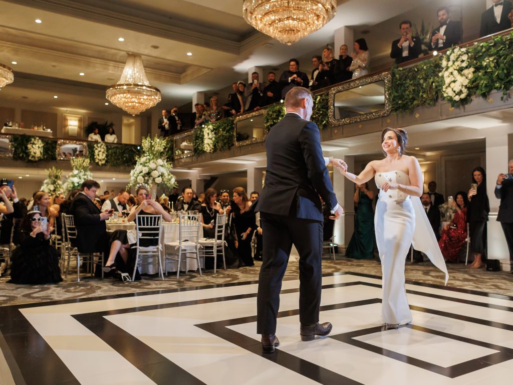 Bride and groom dancing on a black and white dance floor inside Anacacho ballroom