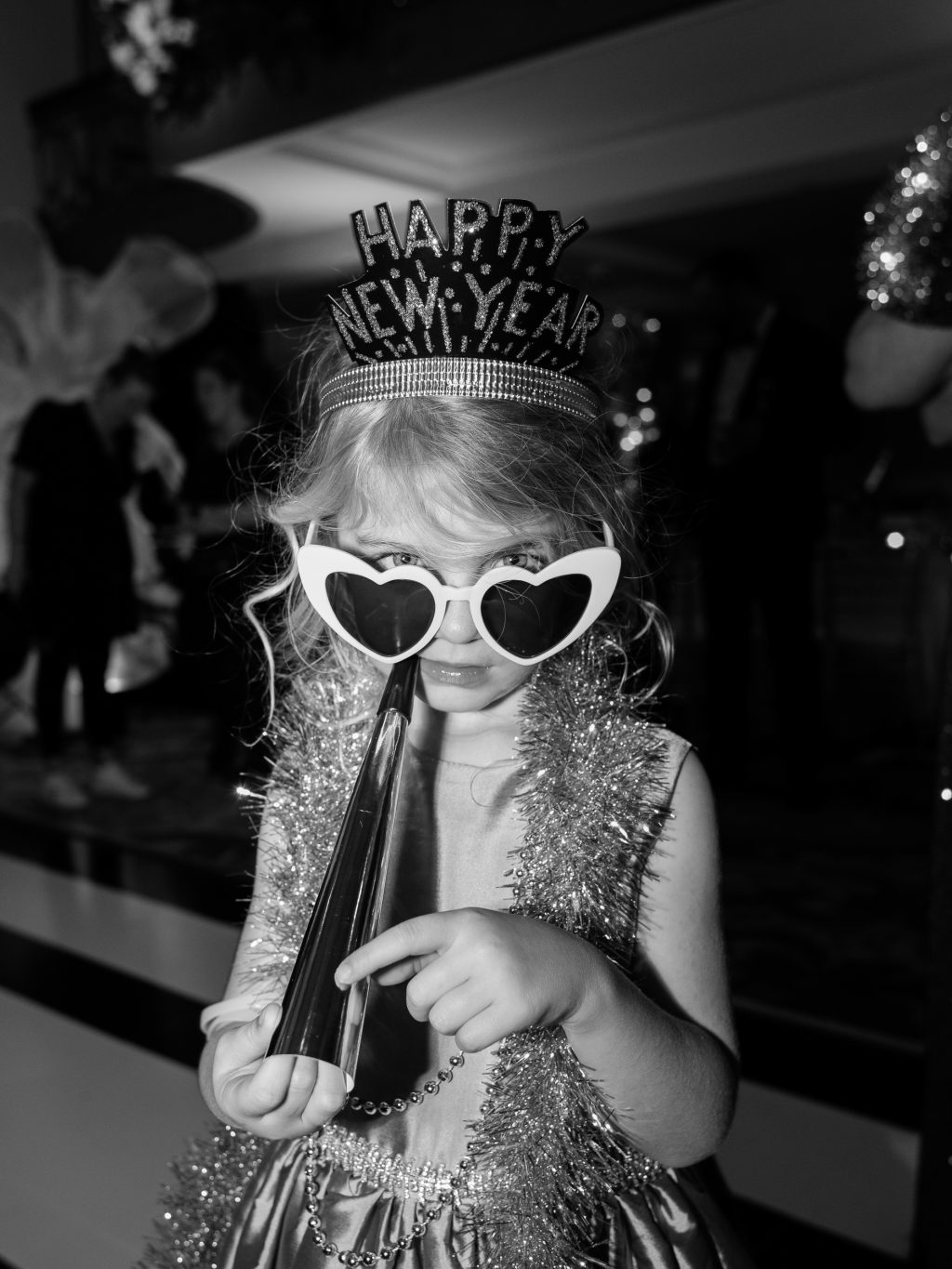 Black and white photograph of a wedding guest wearing Happy New Year glasses