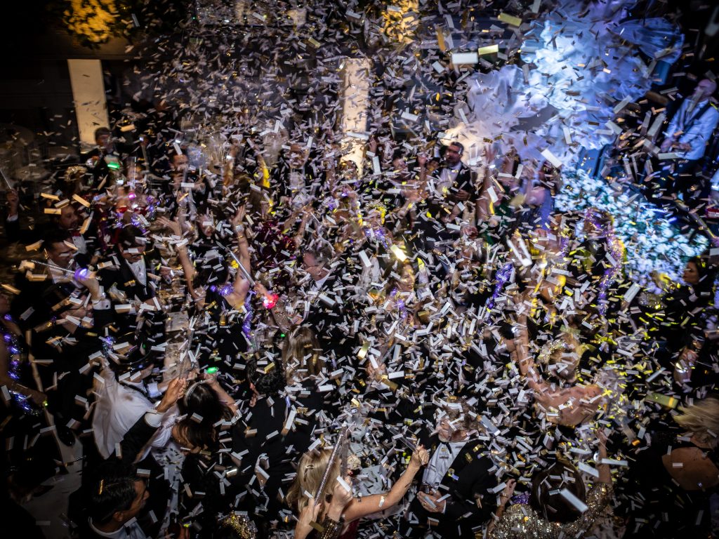 Wedding guests celebrating beneath a burst of confetti at midnight