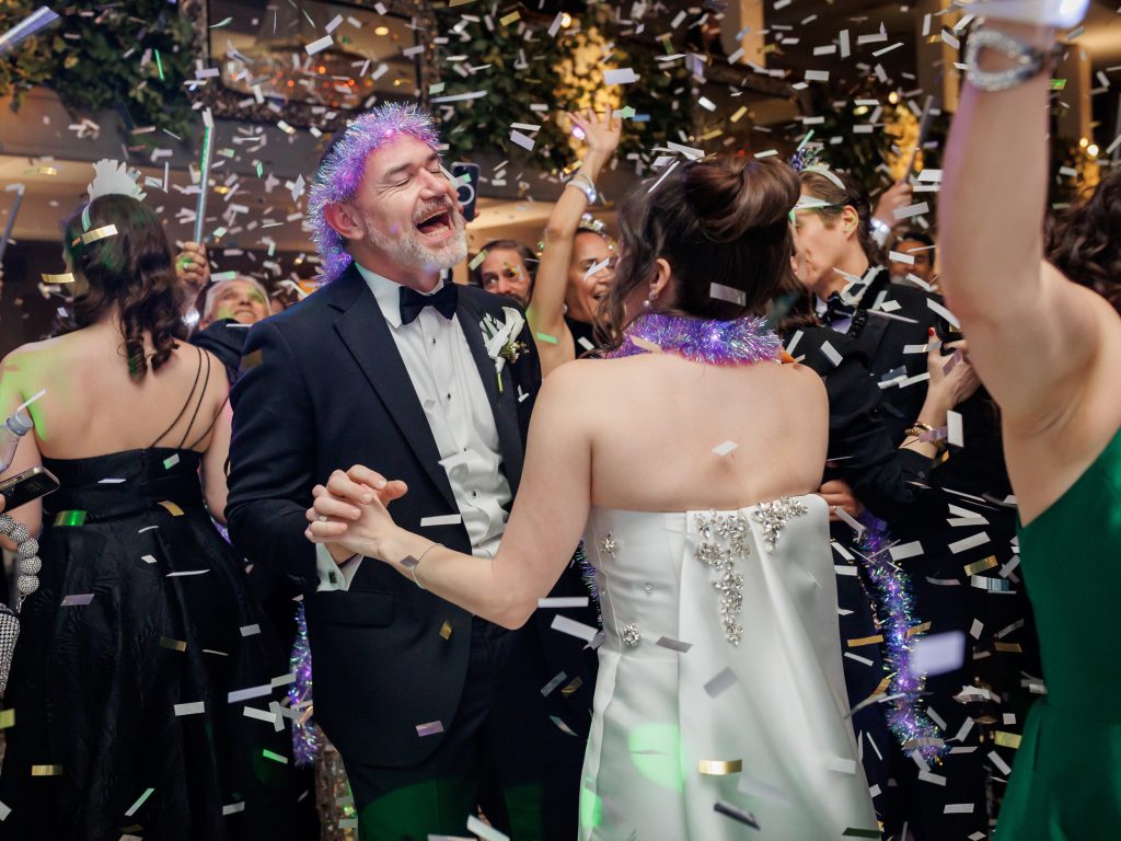 Bride and groom dancing with guests as confetti falls at midnight