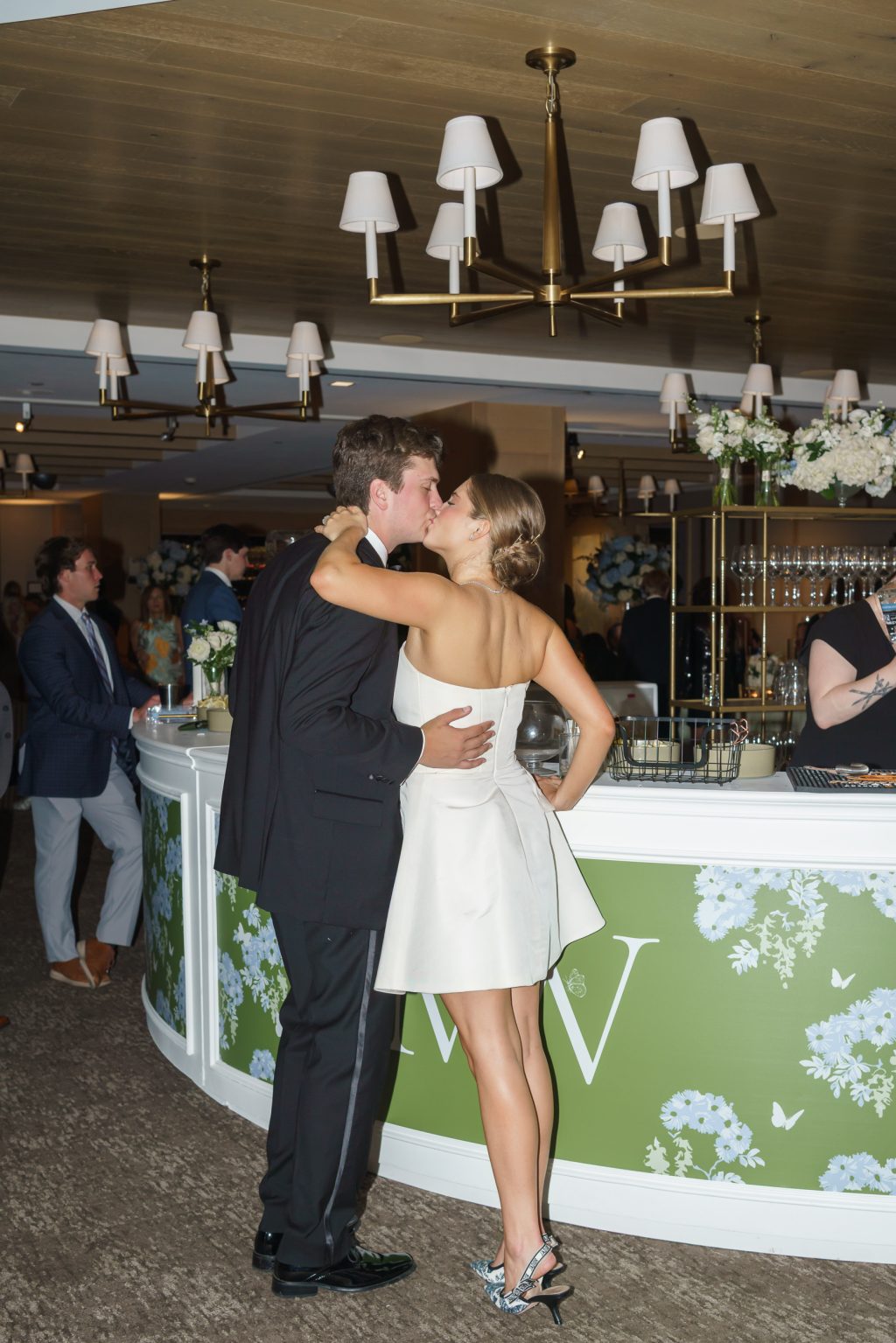 Maddy and Will embrace by their custom bar facade at Westwood Country Club