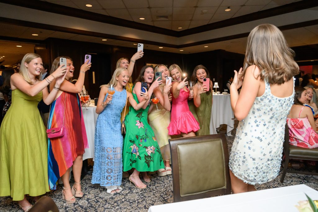Friends cheer during a lively rehearsal dinner toast at the Headliners Club