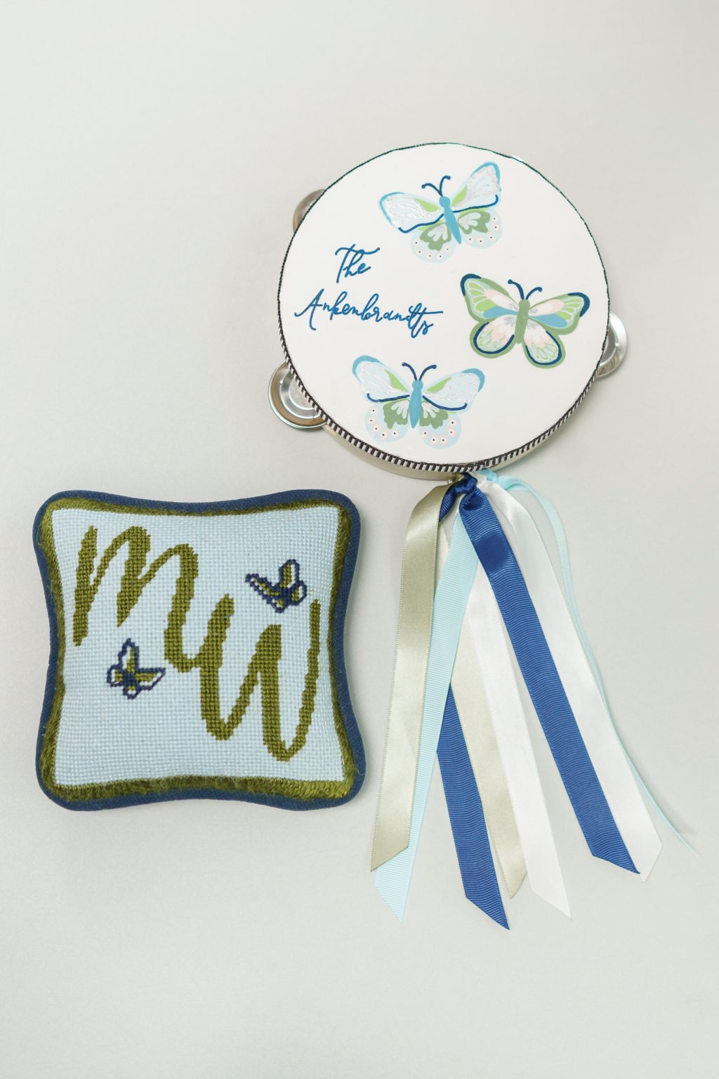Custom butterfly wedding tambourine and monogrammed needlepoint ring bearer pillow detail with blue ribbons