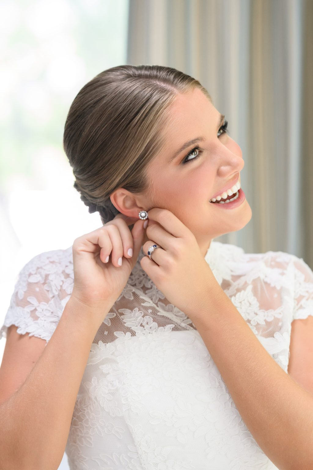 Maddy smiles while putting on her earrings before her Tarrytown wedding ceremony