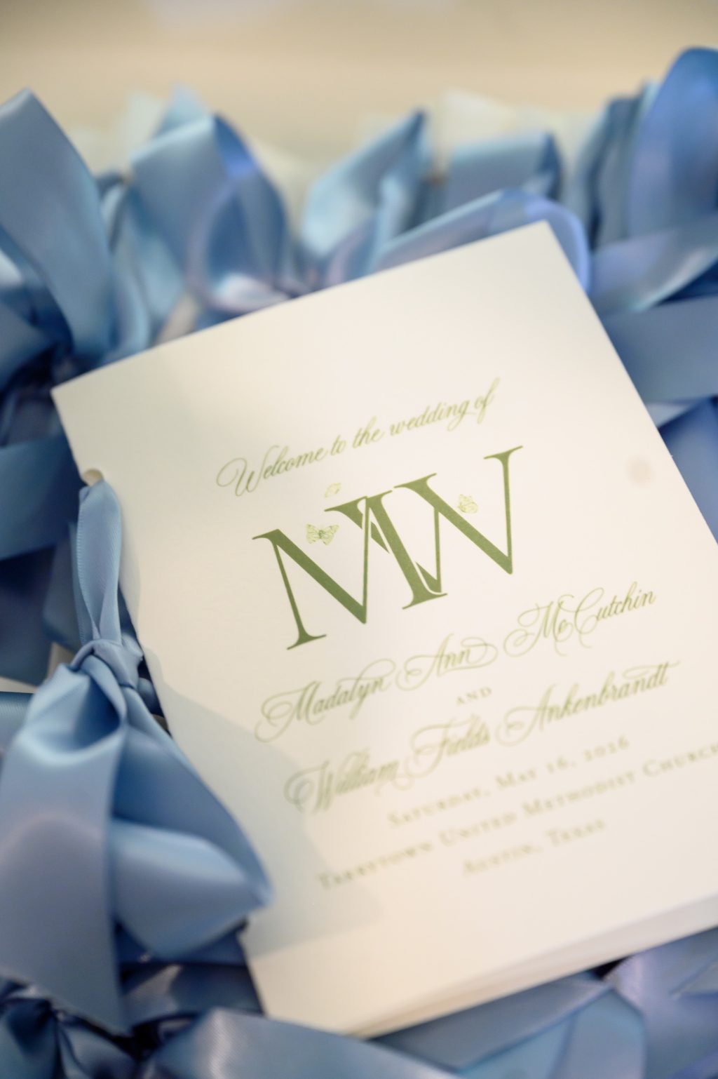 Classic monogrammed wedding ceremony program surrounded by soft blue ribbon