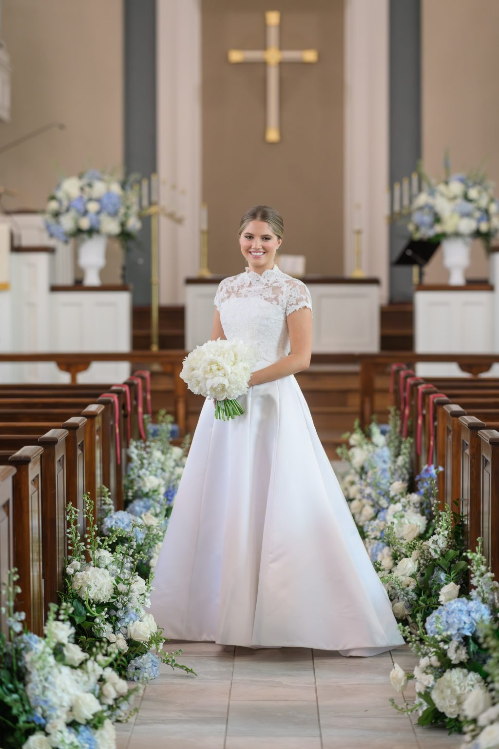 Bride stands between blue and white aisle flowers inside Tarrytown United Methodist Church