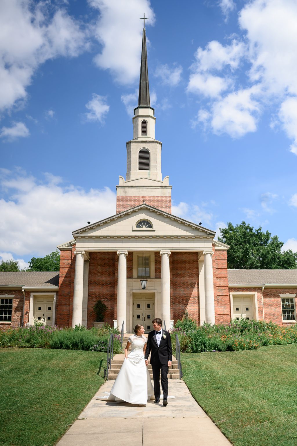Newlyweds stand outside Tarrytown United Methodist Church beneath its white steeple