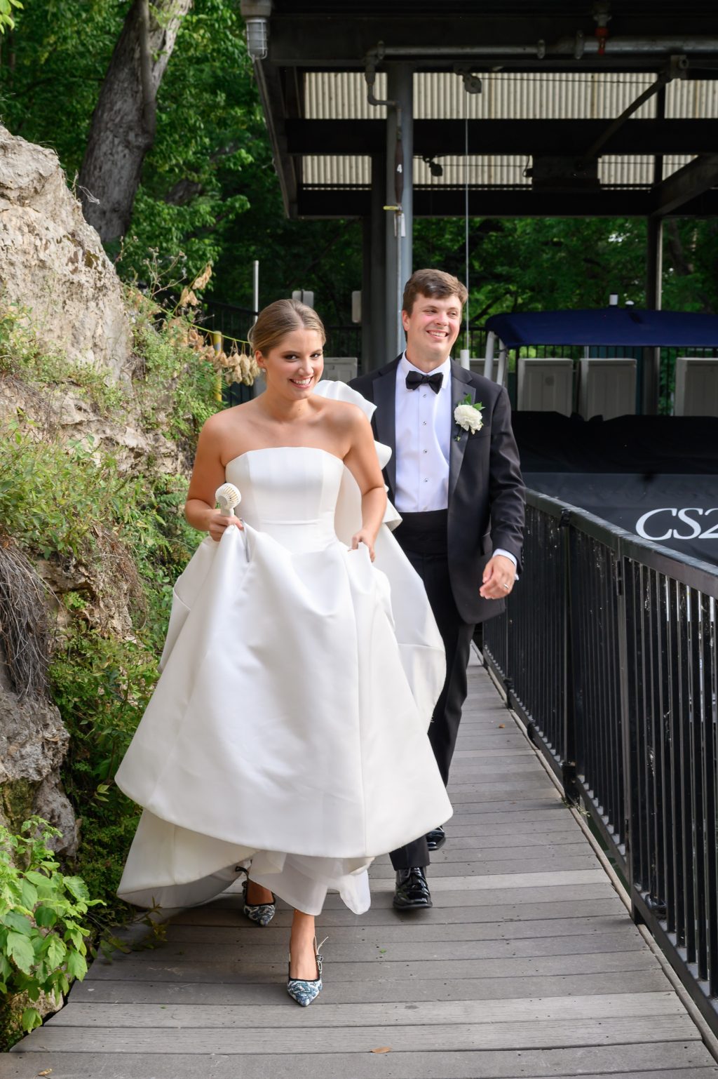 Maddy and Will walk toward their lakeside wedding reception at Westwood Country Club from the boat docks