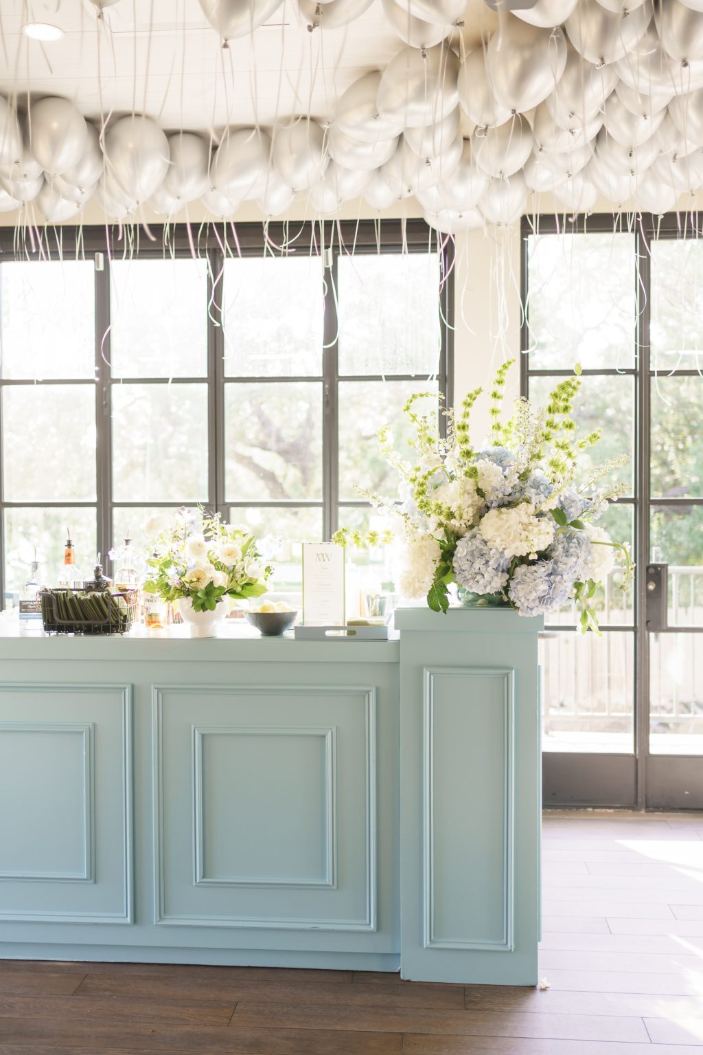 Pale blue reception bar decorated with abundant spring flowers and gathered fabric