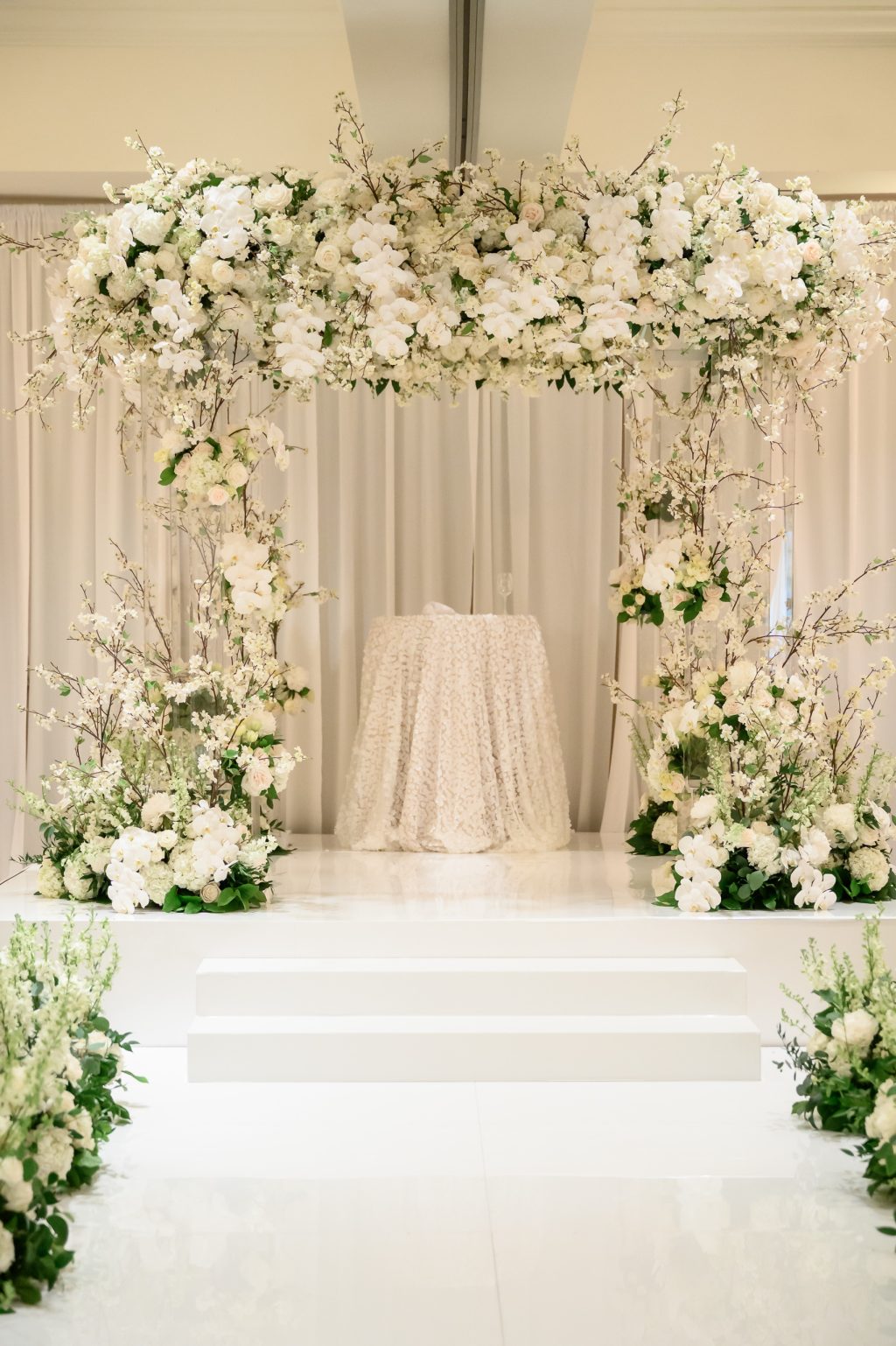 White and green floral ceremony installation with elevated platform at Four Seasons Austin