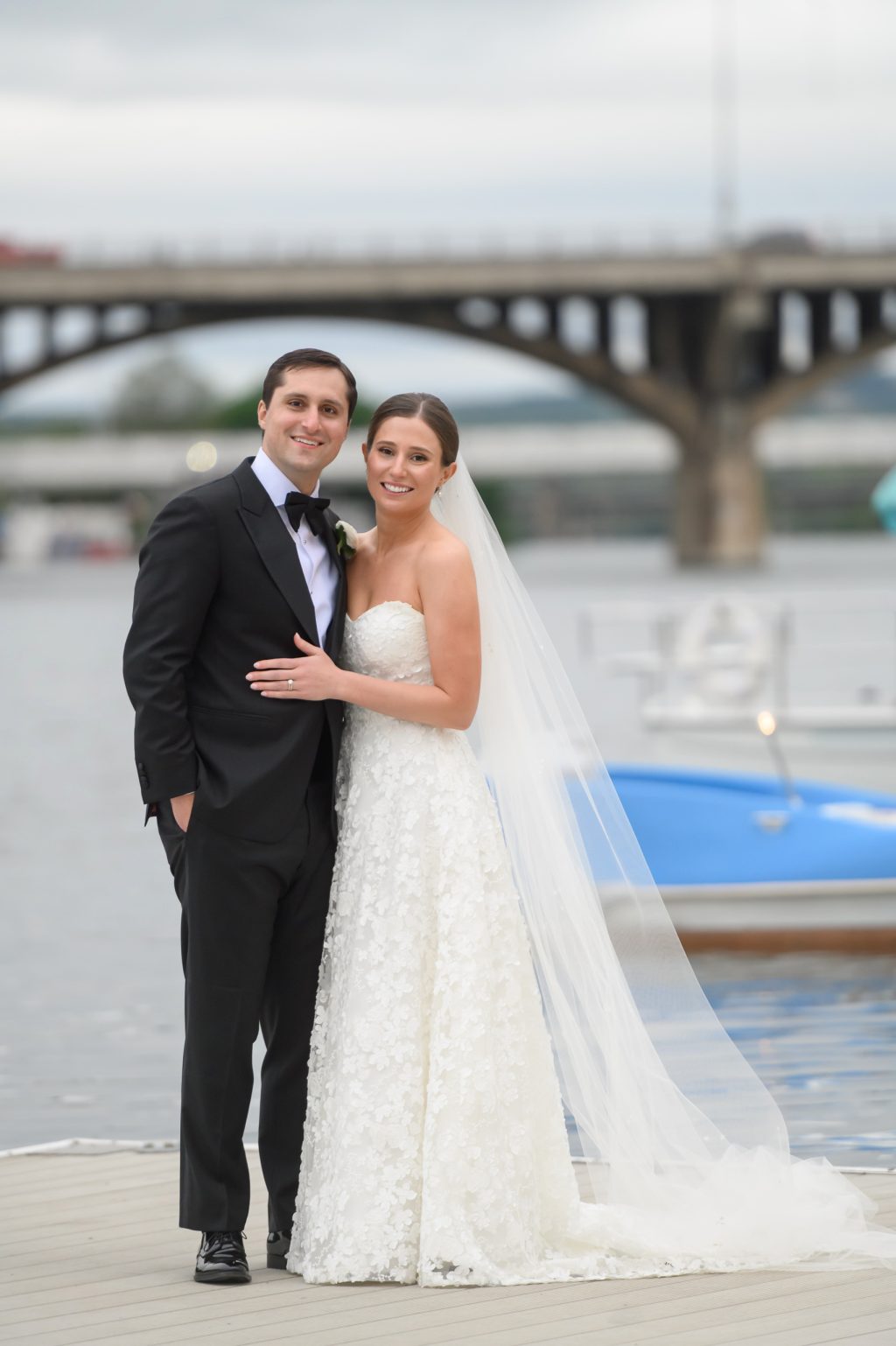 Bride and groom posing on the dock with the Austin skyline and south congress bridge behind them
