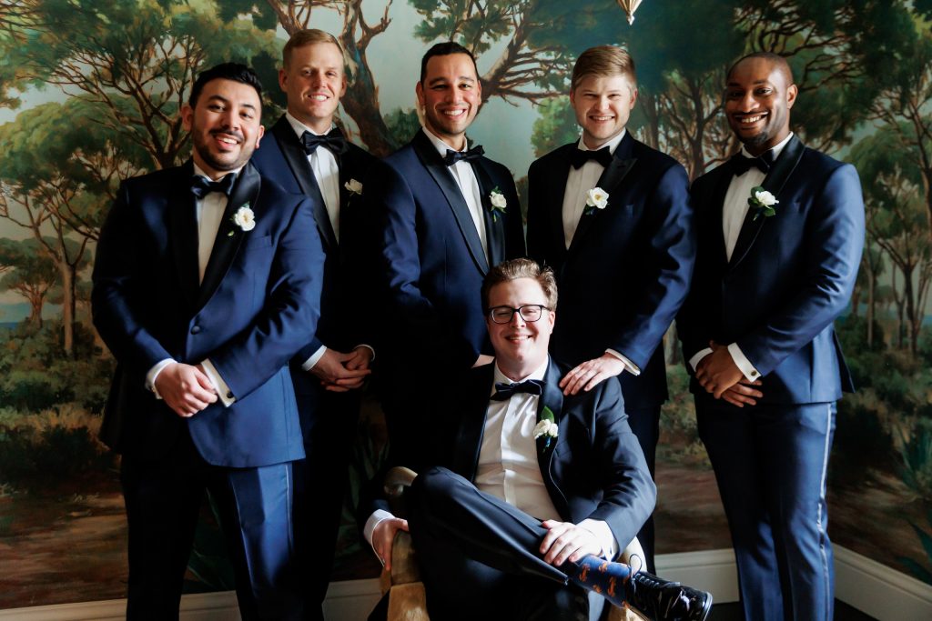 Groom and groomsmen posing together in the Magnolia Suite at Commodore Perry Estate