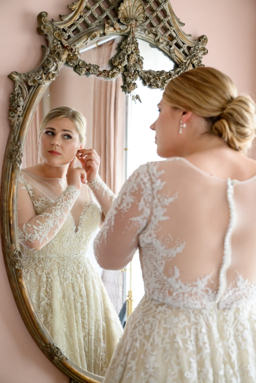 Bride putting on earrings at the mirror in the Mr. and Mrs. Perry Suite at Commodore Perry Estate