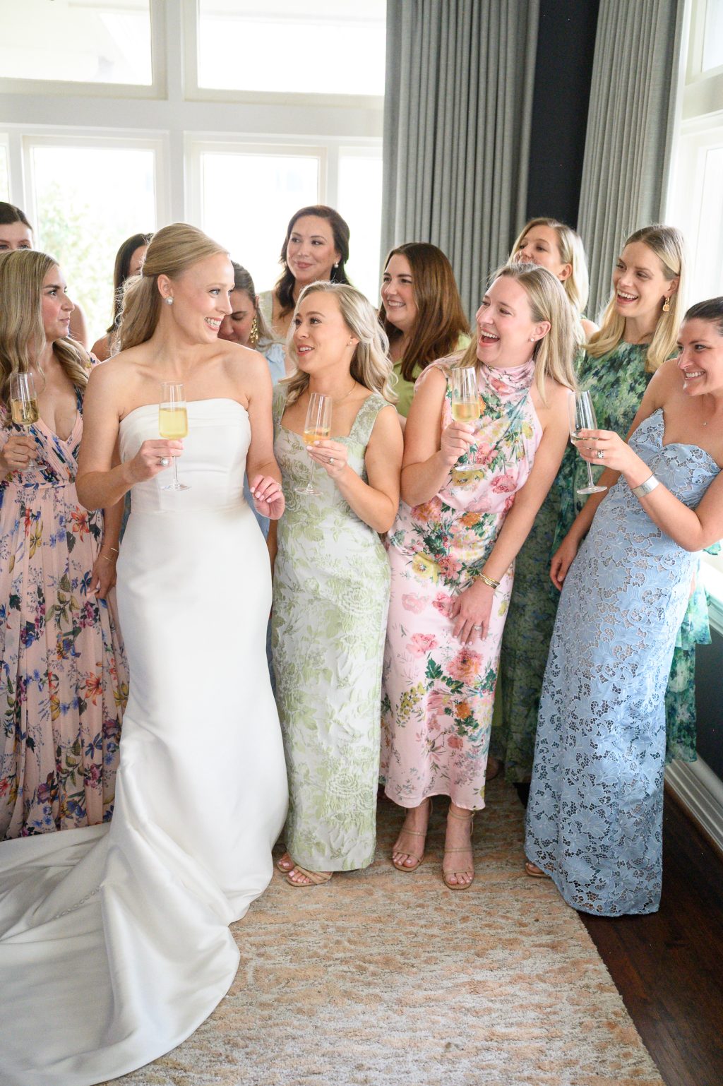 Bride laughing with bridesmaids in colorful floral dresses while getting ready in Houston