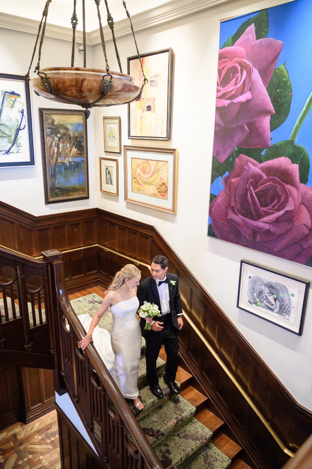 Bride and groom walking down the art-filled staircase inside La Colombe d’Or