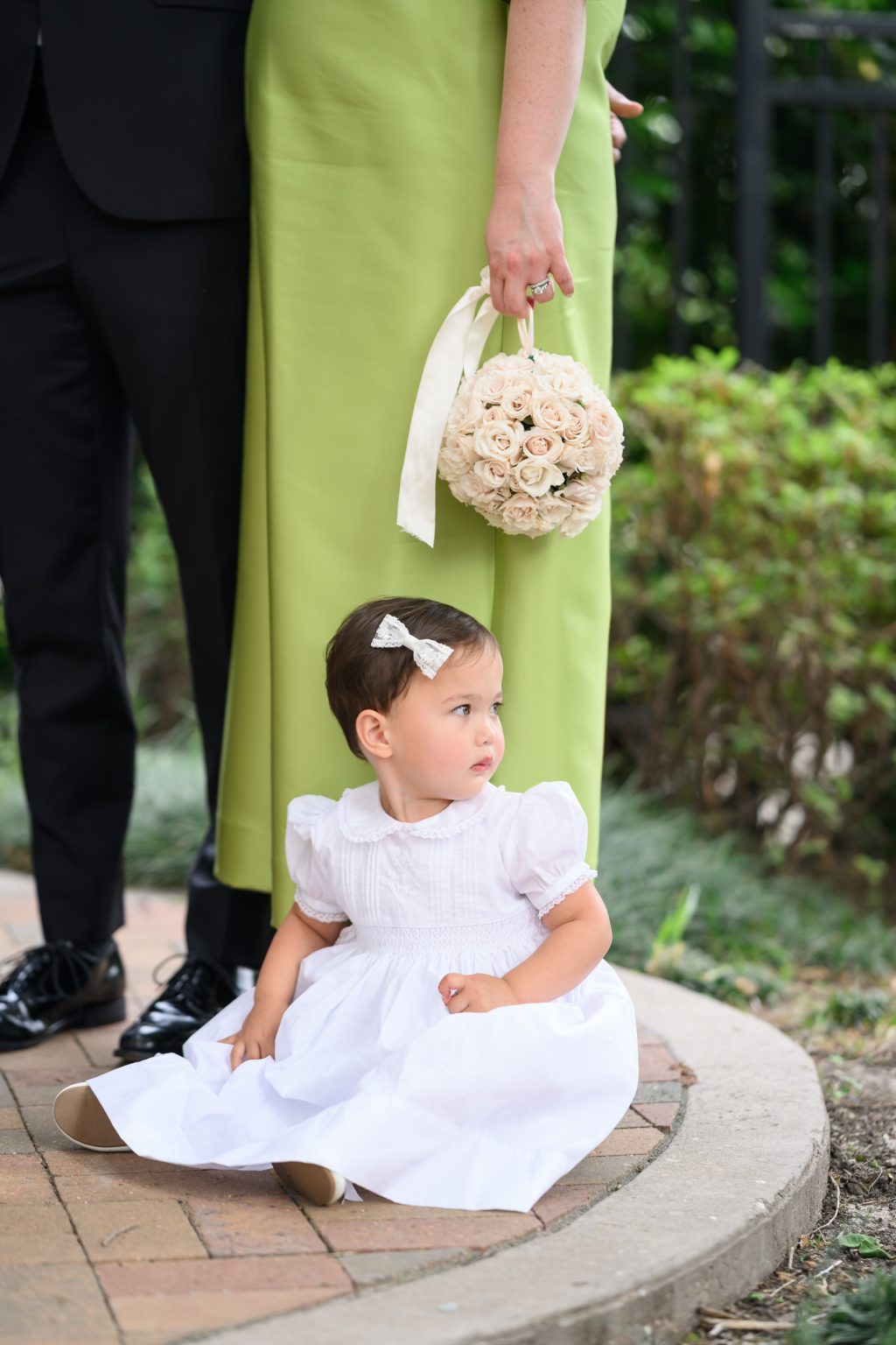 Flower girl in a white dress sitting beside wedding guests at La Colombe d’Or