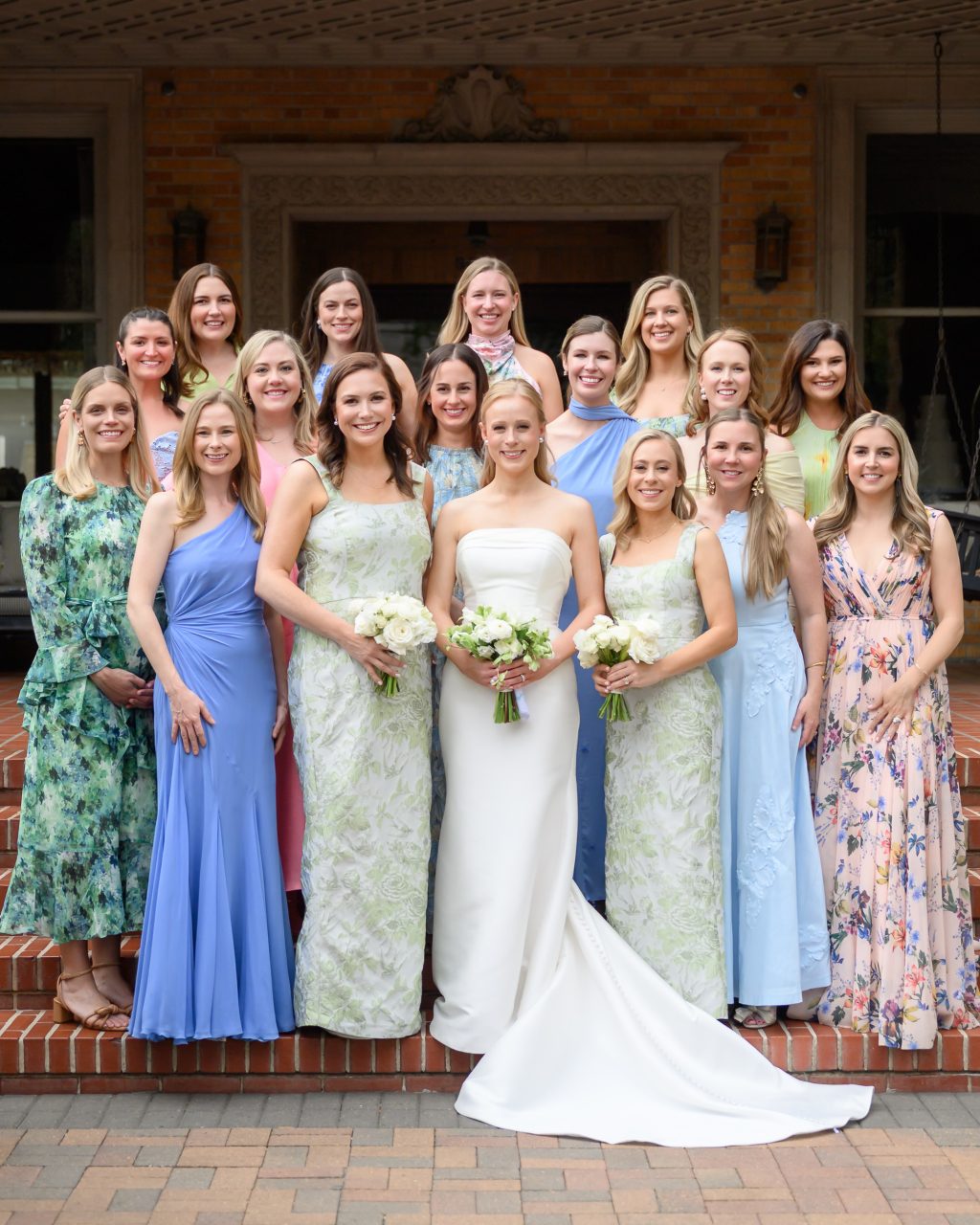 Bride surrounded by bridesmaids in colorful blue, green and floral dresses at La Colombe d’Or