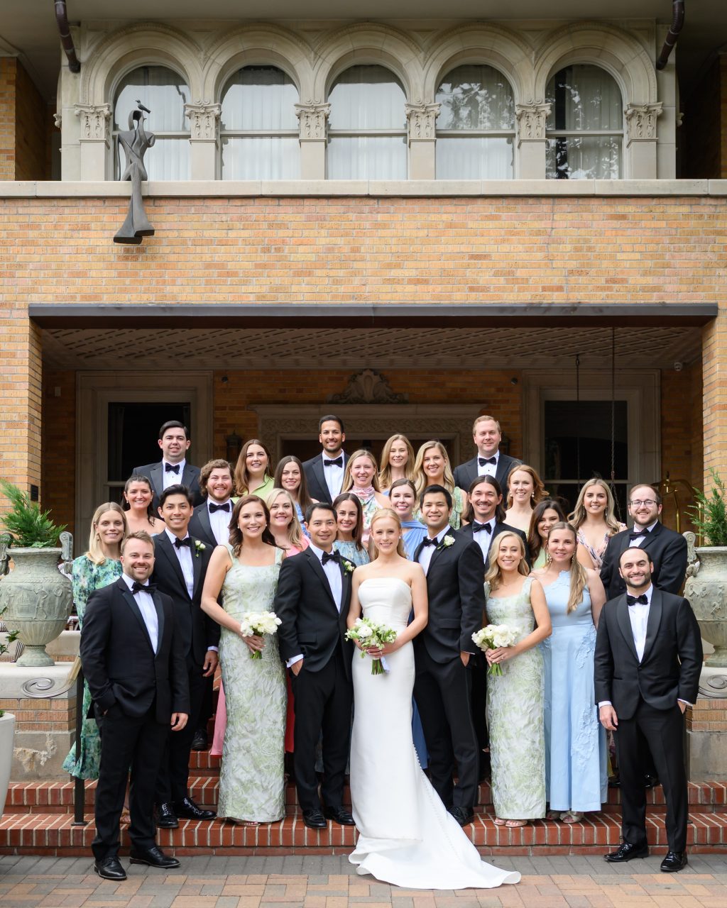 Bride, groom and wedding party gathered outside the historic La Colombe d’Or mansion