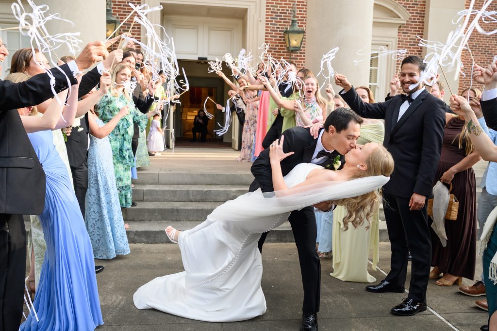 Newlyweds kissing beneath celebratory streamers outside St. Luke’s Methodist Church in Houston