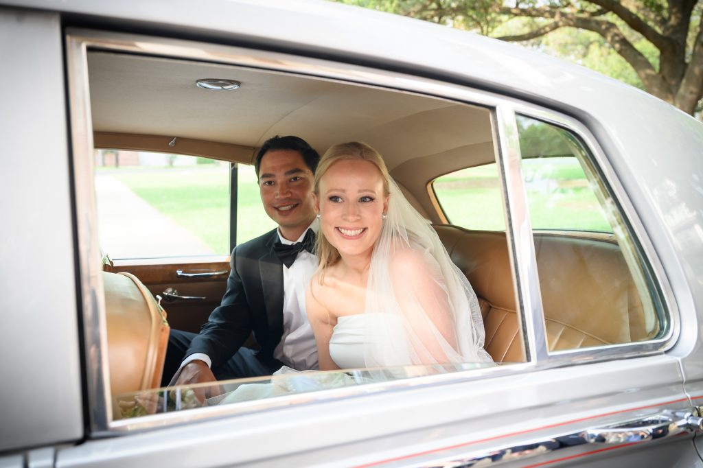 Bride and groom smiling together in their getaway car after the church ceremony