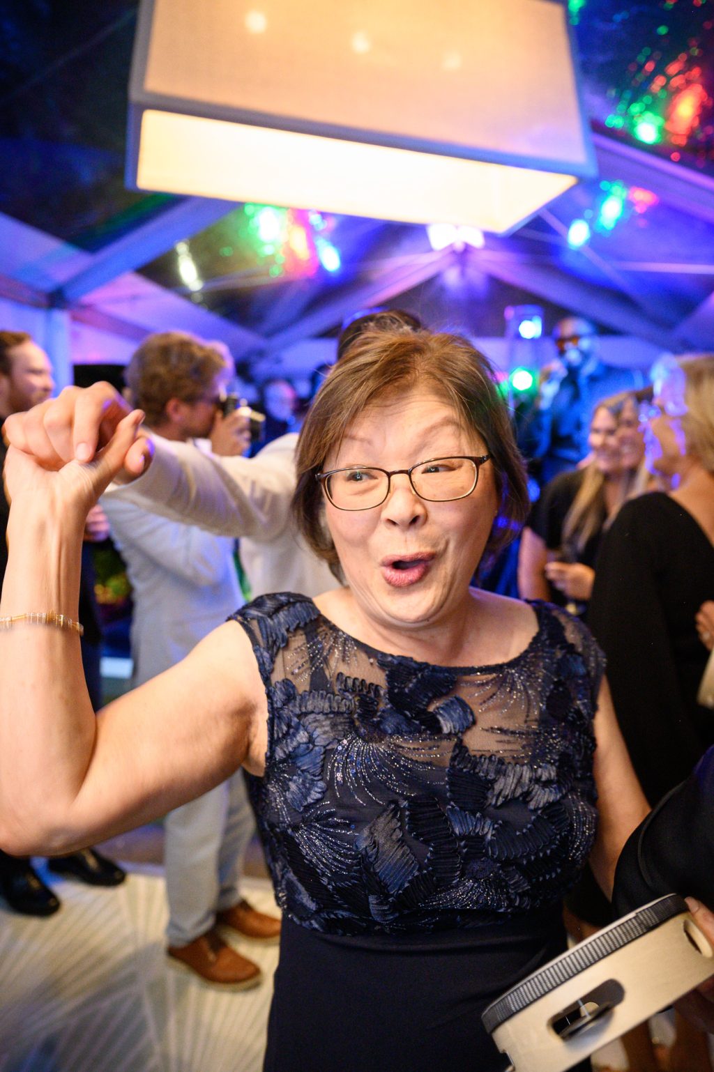 Wedding guest dancing beneath colorful reception lighting at La Colombe d’Or