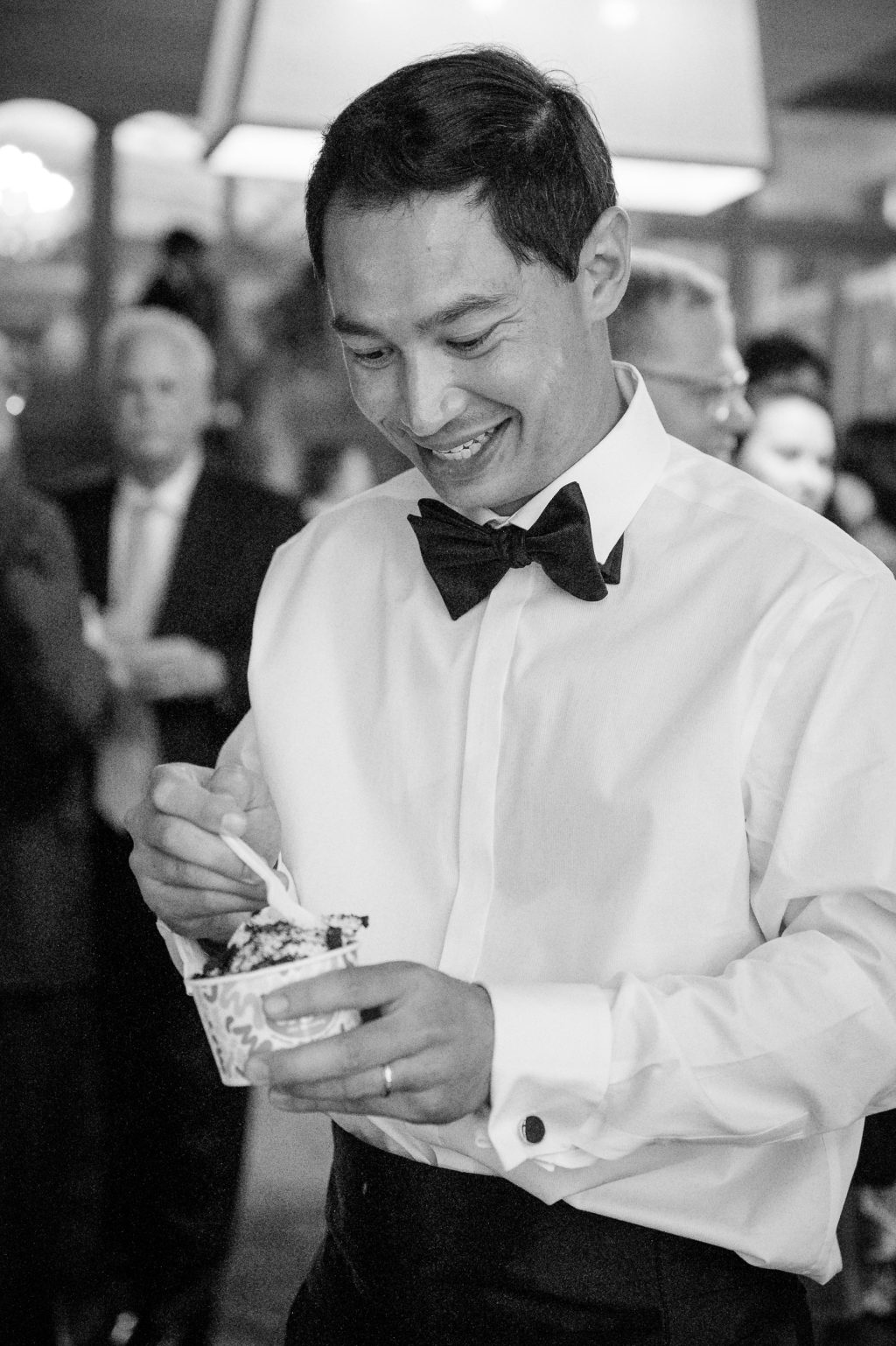 Black and white candid of a wedding guest smiling during the reception
