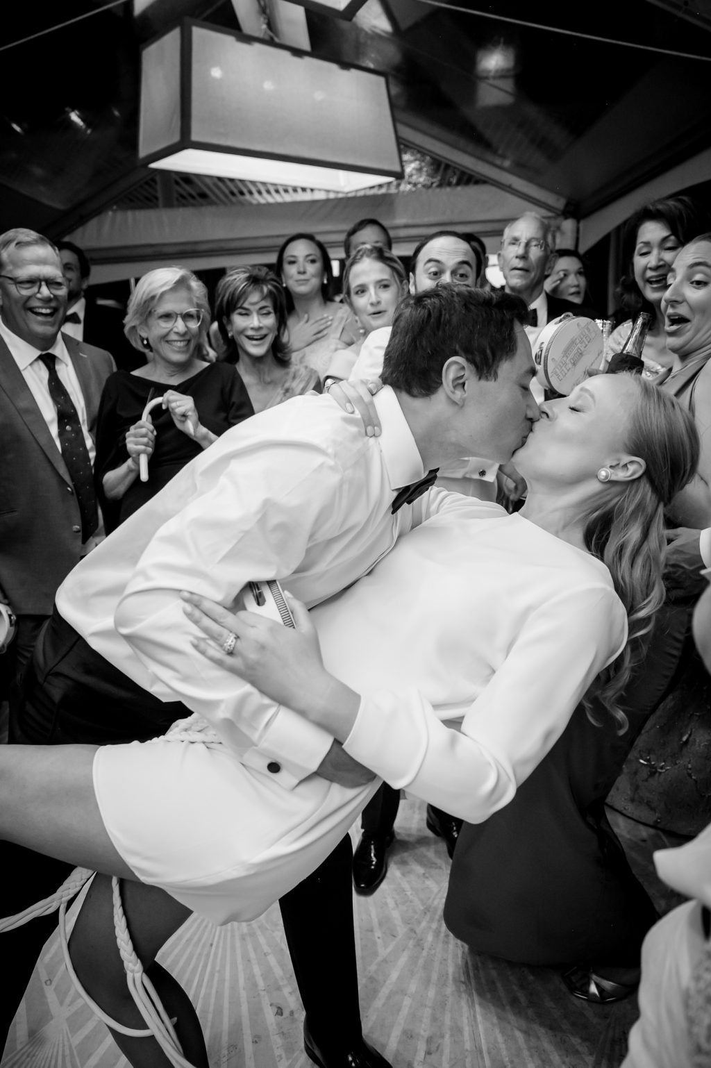 Black and white photograph of the bride and groom kissing during the reception